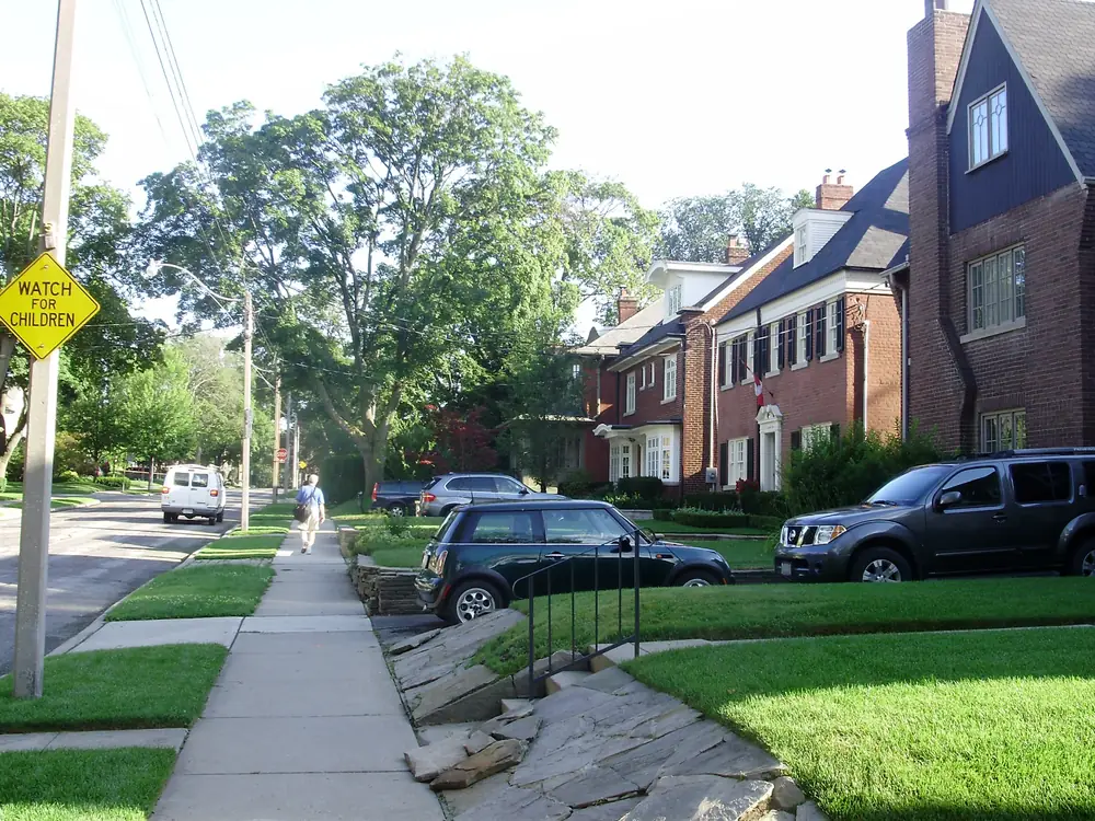 Brick family houses with lawns and parked cars on Lascelles Boulevard in Chaplin Estates, Midtown Toronto