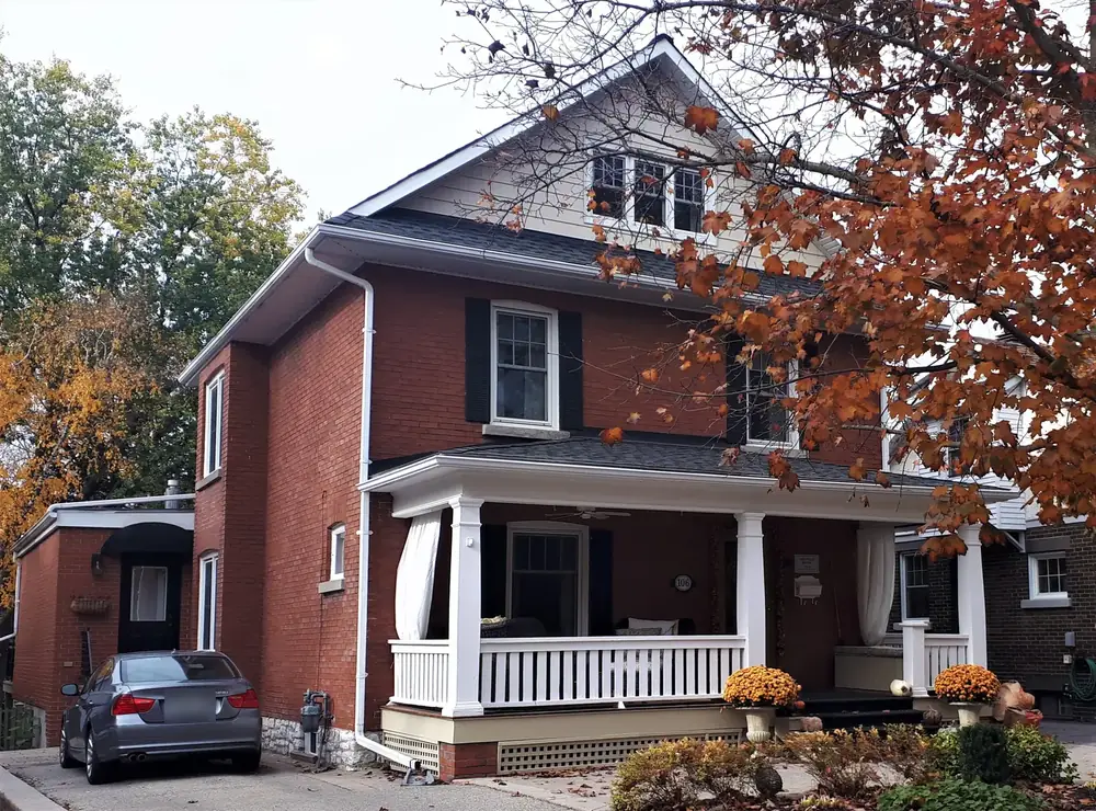 The Pugh House, an Edwardian red-brick home with a white front porch on Wells Street in Aurora, in autumn
