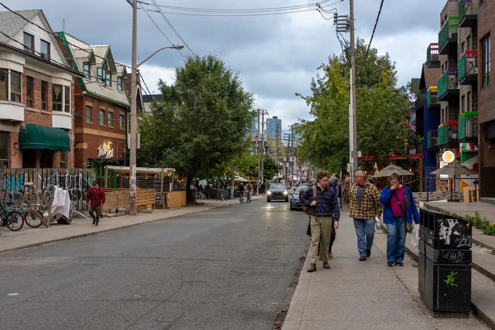 Looking along Augusta Avenue in Kensington Market, Toronto, with brick houses, shops and trees
