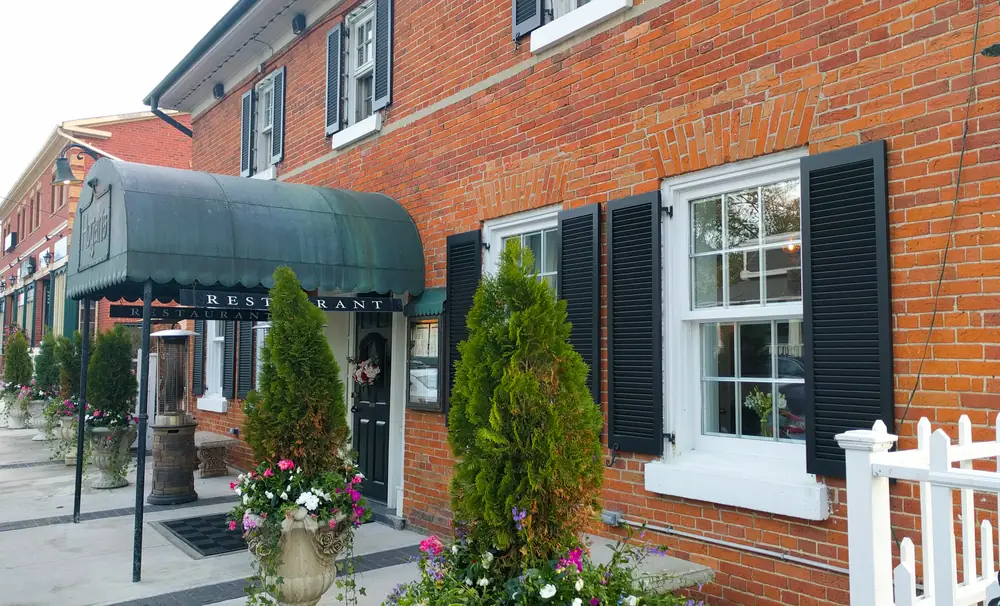 A red-brick heritage building with black shutters and a green awning in King City