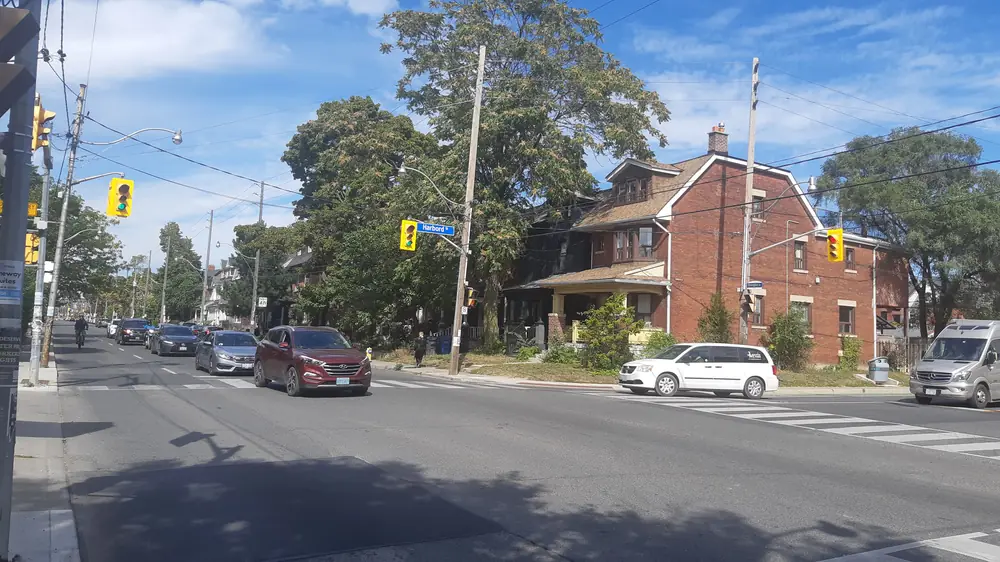 Ossington Avenue near Queen Street West, with a brick house on the corner and parked cars, Toronto