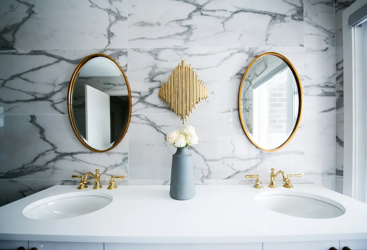 A gleaming white-marble bathroom with a double vanity and brass fixtures