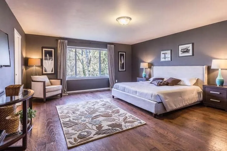 A tidy bedroom with a freshly made bed and hardwood floors