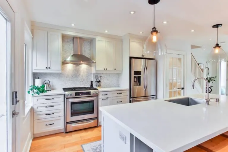 A clean white kitchen with a stainless-steel range and island