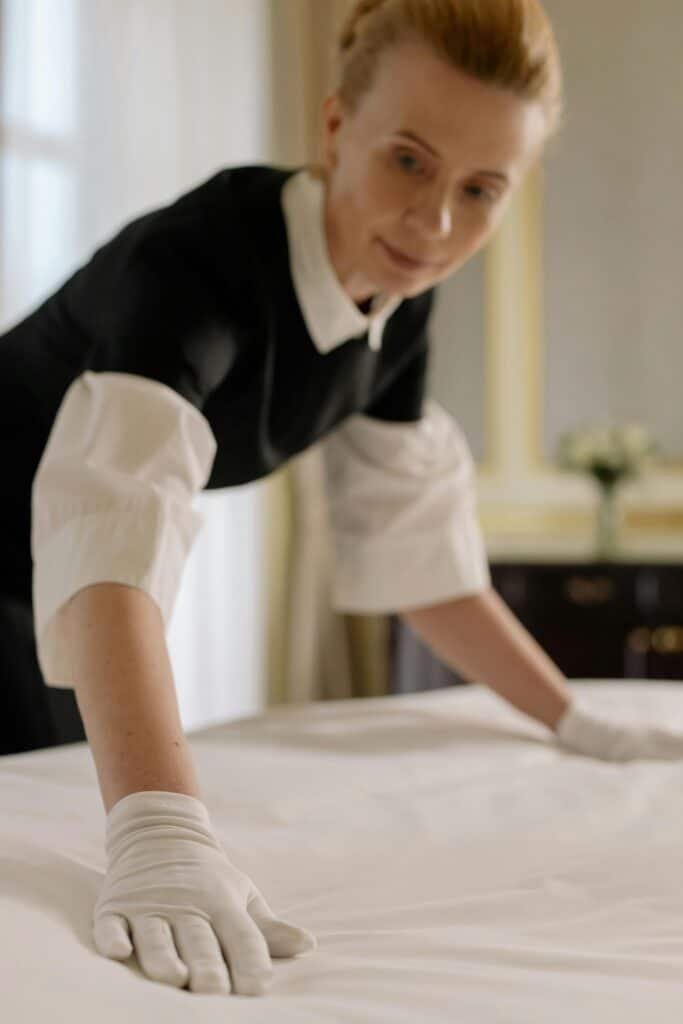 Maid organizing a bed with white gloves