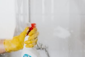 Sanitizing something using spray and yellow cleaning gloves