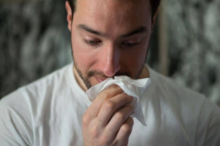 Man sneezing on a tissue paper looking down