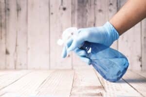Cleaning something with spray, wearing blue cleaning gloves