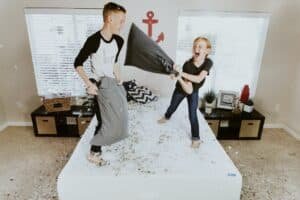 2 kids playing on the bed