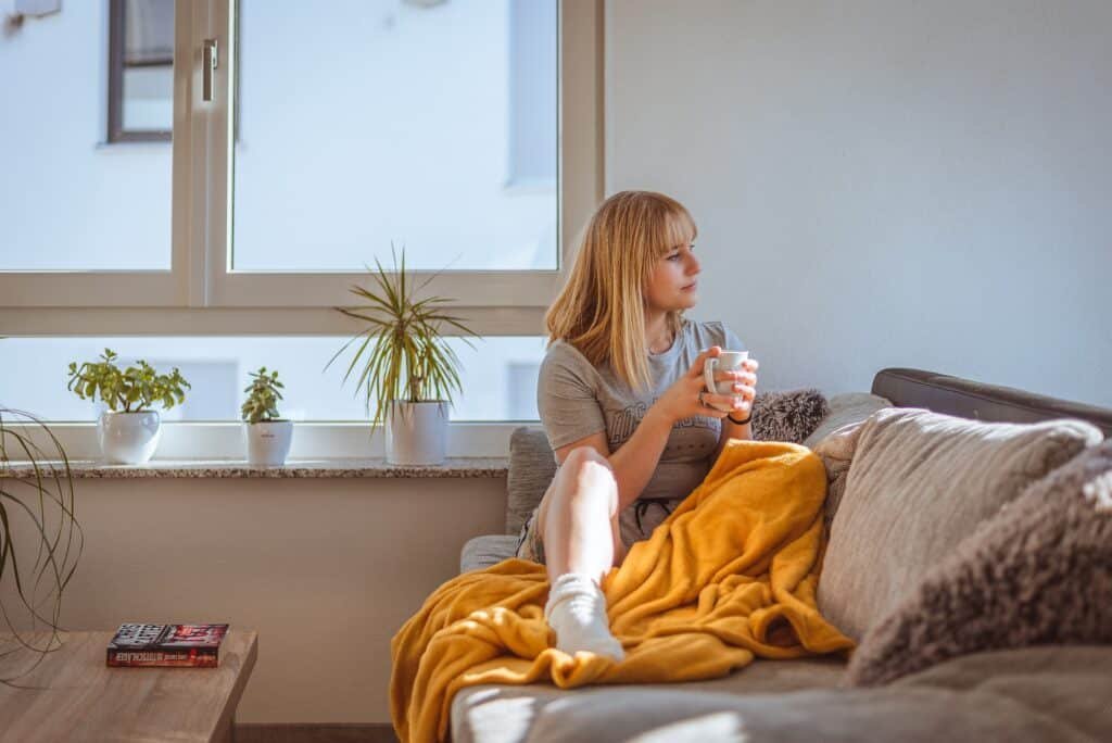 Woman with blanket and coffee on couch