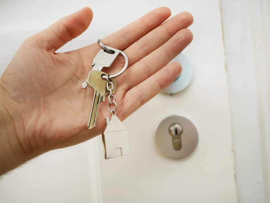 person holding a house key with house keychain apartment turnover