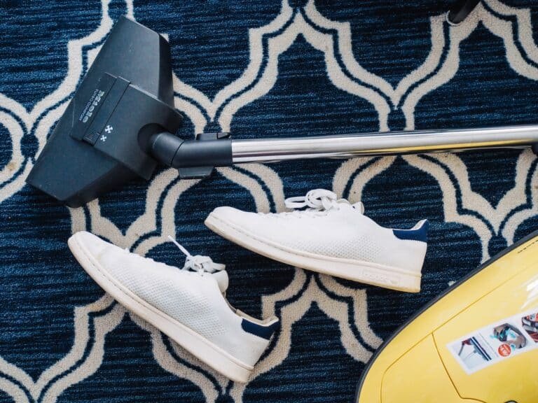 Vacuum cleaner and sneakers on a carpet indoors