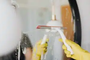Cleaning mirror with mild soap using yellow cleaning gloves, Post-Construction Cleaning