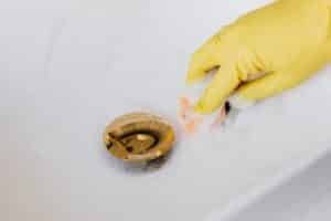 Drain being cleaned, yellow cleaning gloves, foam