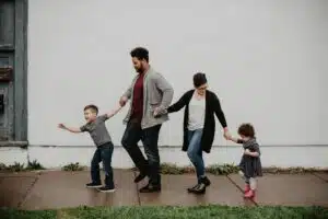 Family holding hands, parents with two kids.