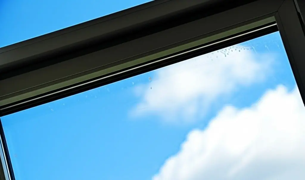 Streak-free window pane framing a blue sky with white clouds
