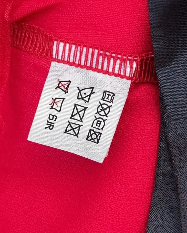 Garment care label with laundry symbols sewn into a red shirt