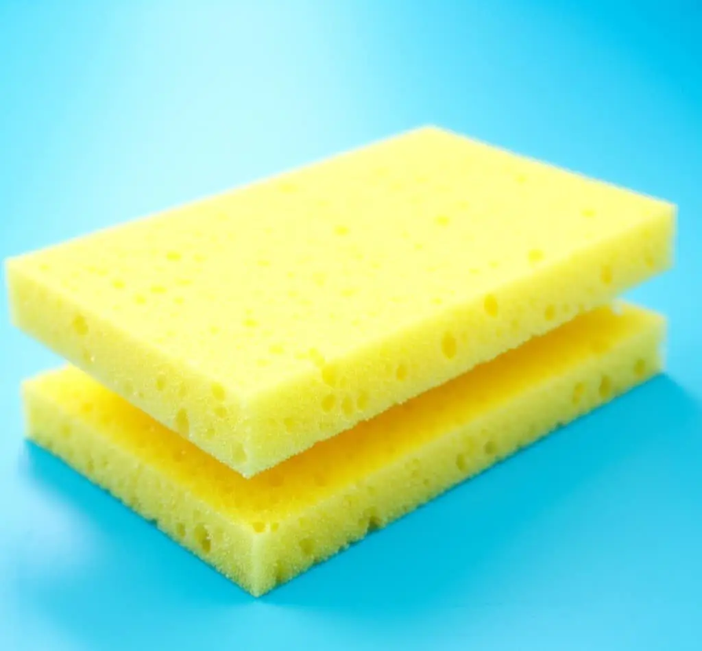 Two yellow cellulose sponges stacked on a blue background