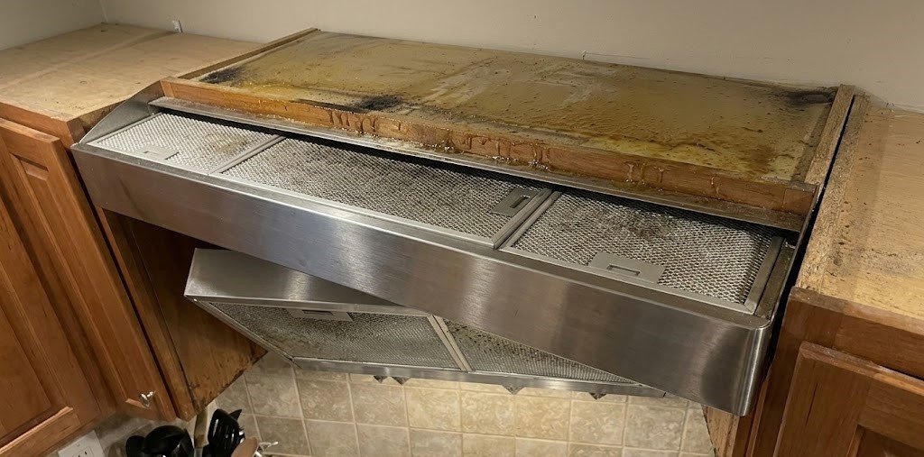 Tops of cabinets are dirty due to the kitchen range hood filter.
