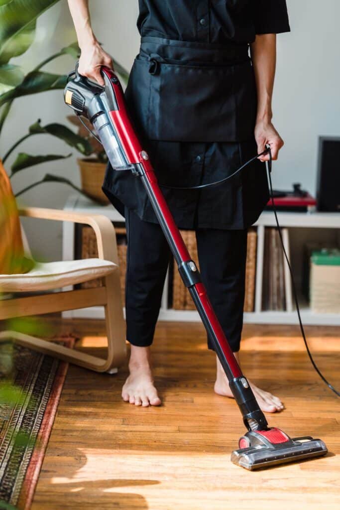 Professional cleaner vacuuming a living room floor
